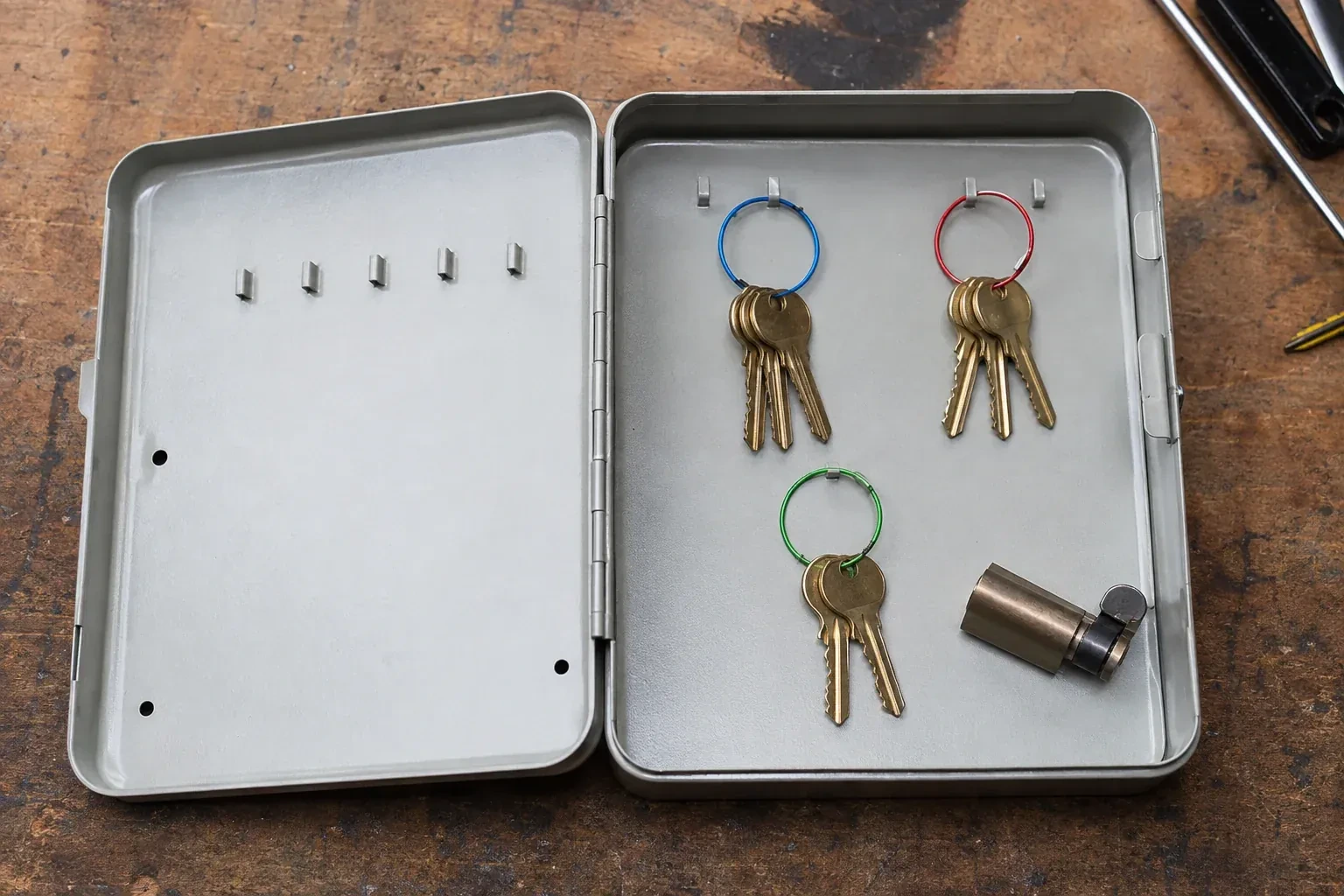 Three groups of keys on colored rings in an open metal key cabinet. — Master Key System Design, Burlington